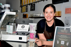 A woman at the counter of a barlour with boozy ice cream products on display.