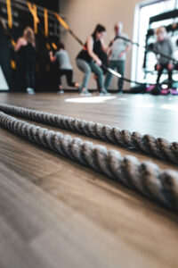 Battle ropes on a gym floor with people exercising in the background