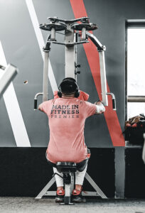 Person using gym equipment wearing a "Made in Fitness Premier" shirt