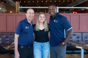 Three professionals smiling together in a casual setting - SMB Franchise Advisors