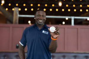 Smiling man holding a baseball with SMB logo - SMB Franchise Advisors