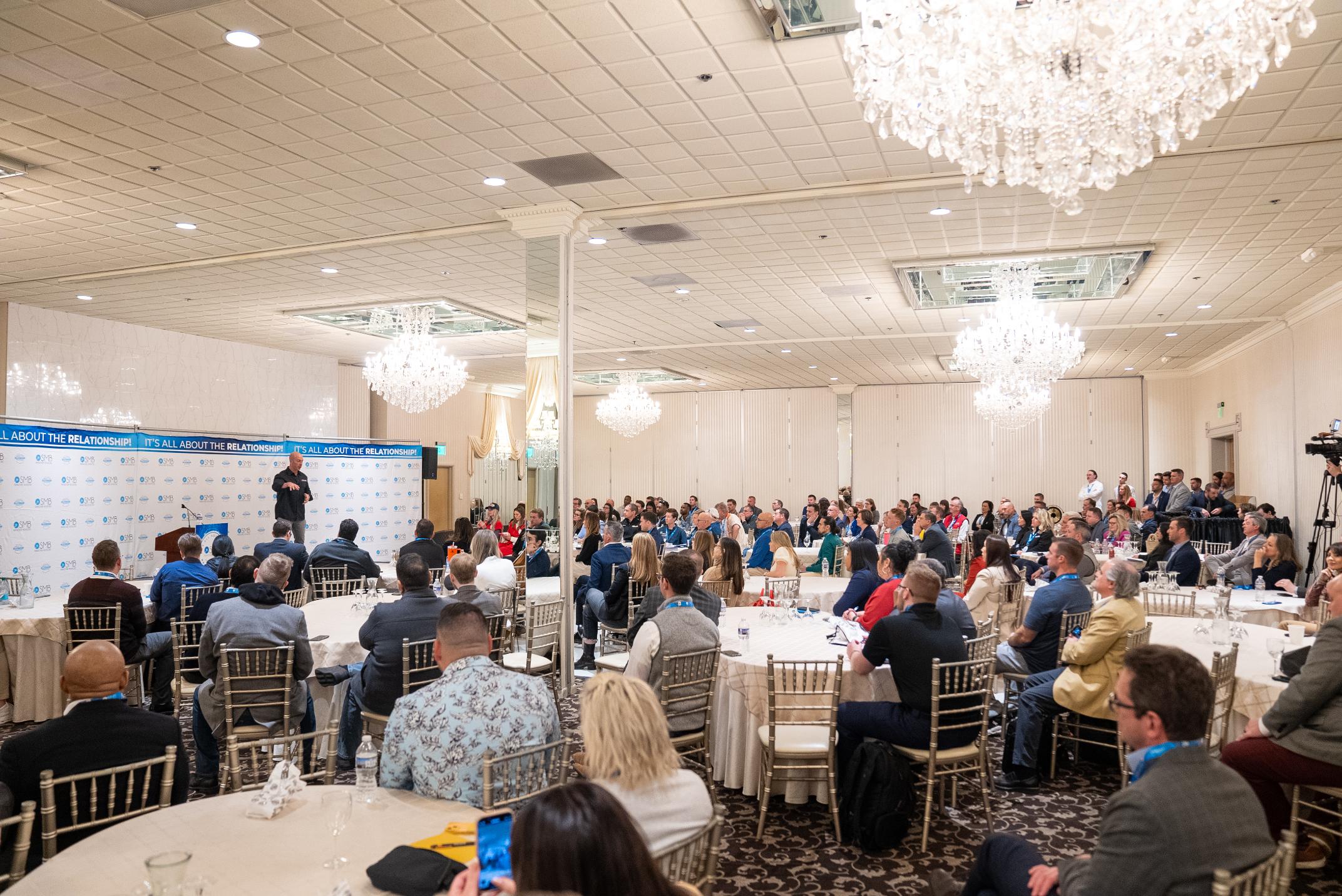 Conference audience engaged with speaker on stage - SMB Franchise Advisors